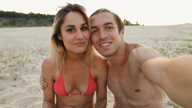 young couple doing selfie on the beach at sunset