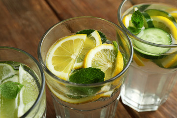 Fresh cocktails with soda, lime, lemon and cucumber on a wooden background
