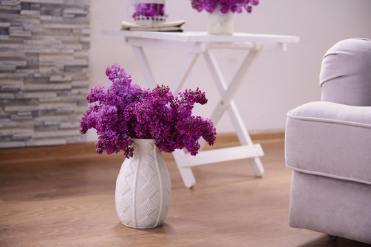 Lilac bouquet in ceramic jar on wooden floor