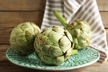 Artichoke on plate on wooden background