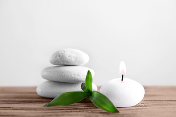 Fototapeta na wymiar White spa stones with candle on light background