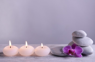 Obraz na płótnie Canvas White spa stones with candles on gray background