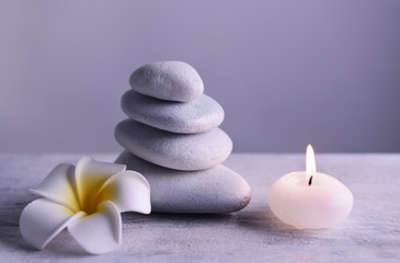 Fototapeta na wymiar White spa stones with candle on gray background