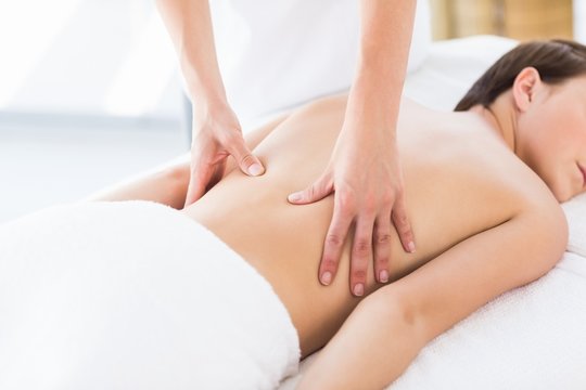 Naked woman receiving back massage