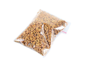 Fenugreek seeds in plastic zipper bag, isolated on white