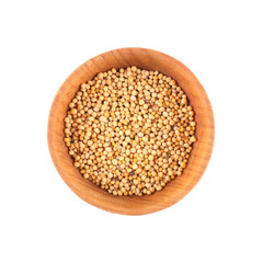 Mustard seeds in small wooden bowl isolated on white