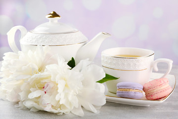 Cup of tea with macaroons and peonies on wooden table