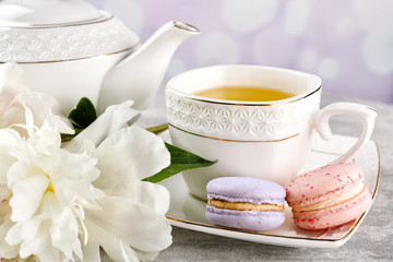 Cup of tea with macaroons and peonies on wooden table