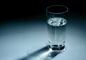 Glass and some mineral water on blue background