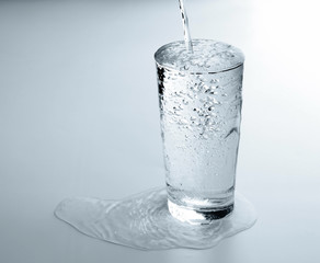 Pouring water into glass on white background