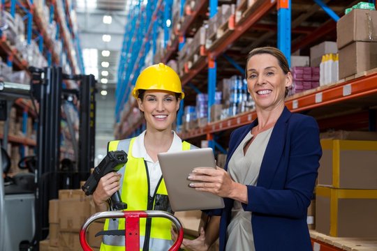 Businesswoman and warehouse worker looking at camera
