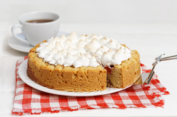 Sweet cake decorated with meringue and cup of tea