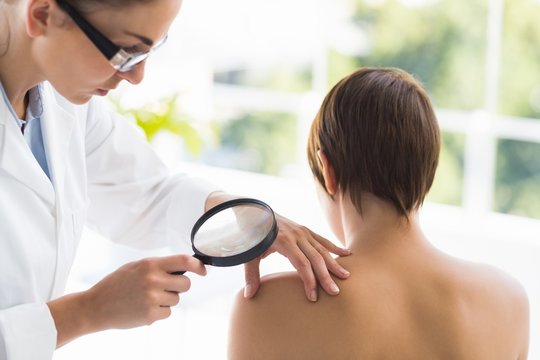 Doctor Examining Woman Back With Magnifying Glass