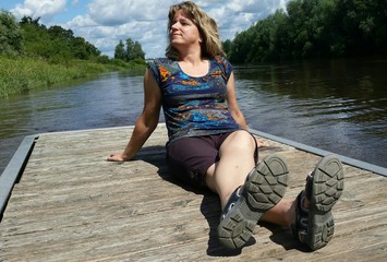 Frau sitzt auf Bootssteg und genießt die Sonne zur Sommerzeit