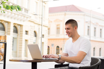 Portrait of an attractive man smiling with laptop outside