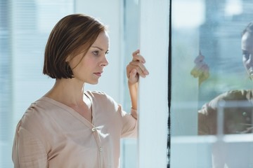 Thoughtful woman standing by glass