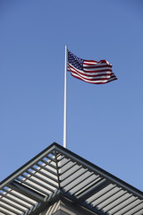 american flag installed on a roof in front of blue sky