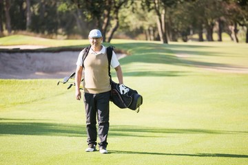Sportsman walking with his golf bag