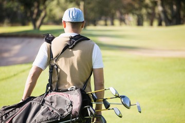 Rear view of sportsman holding a golf bag