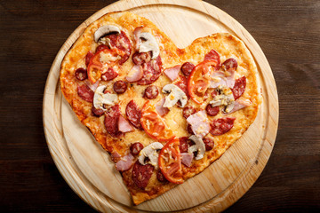 Pizza heart shape on dark wooden background top view