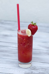 Strawberry smoothie in the glass with straws on wood background