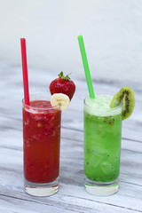 Strawberry and kiwi smoothies in the glasses with straws on wood background