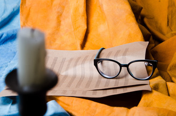 still life of glasses, notes and a candle on the background of the folds of the red and blue fabric