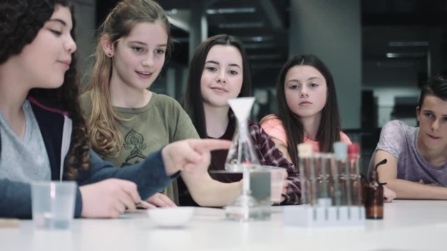 Group of girls practice chemistry at school