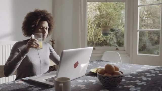 Afro American woman buying online on laptop in kitchen
