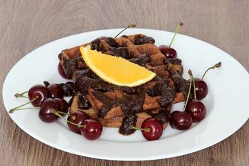 Sweet chocolate belgian waffles. Close up of chocolate waffle. Fresh delicious homemade waffles. Chocolate waffles with chocolate frosting on top with fresh cherry. Shallow depth of field.