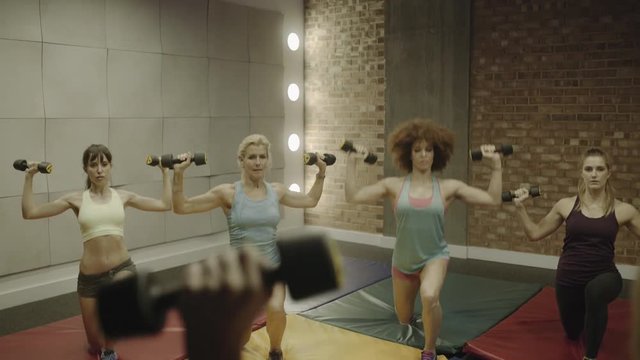 Group of adult women exercising with weights in gym