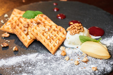 A delicious dessert of Belgian waffles and ice cream served on a stone Board