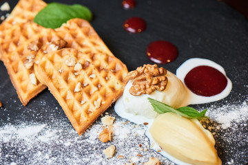 A delicious dessert of Belgian waffles and ice cream served on a stone Board