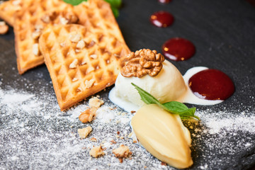 A delicious dessert of Belgian waffles and ice cream served on a stone Board