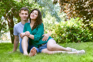 Fototapeta premium Romantic couple sit on grass in city park, summer season, lovers boy and girl