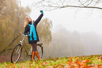 Obraz premium Happy woman with bike in park taking selfie photo.