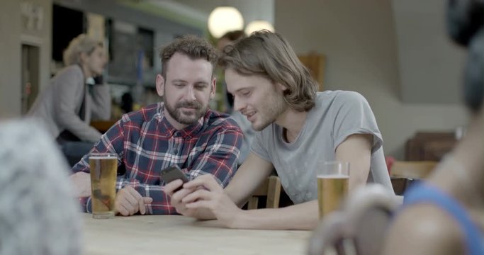 Men drinking beer and talking with each other while sitting in pub