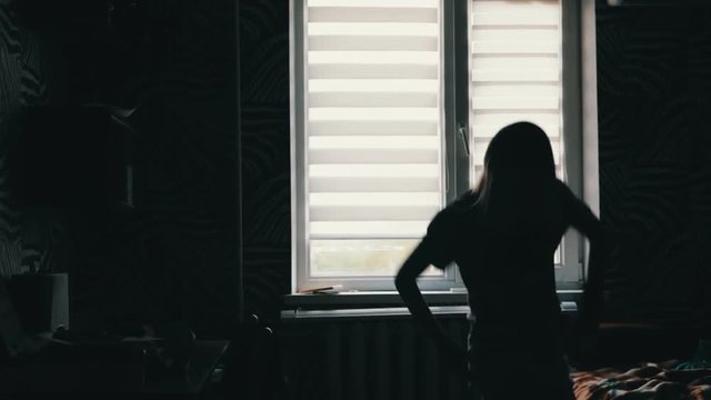 silhouette of a girl dancing in front of a window at home