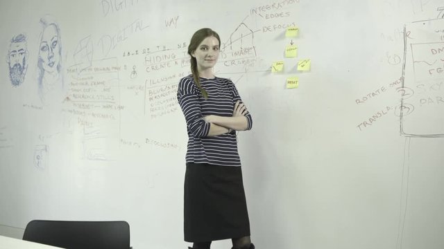 Young woman sticking adhesive note on notice board in office
