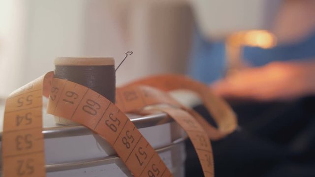 tape-measure and black thread reel, sewing machine is on background