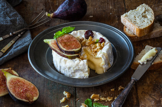 Camembert cheese with fresh figs, walnuts, raisins and honey. Rustic retro vintage ambiance.