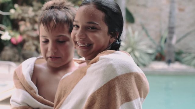 Sibling wrapped in towel and enjoying near swimming pool