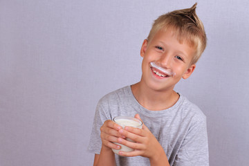 Funny young boy with mustache from yogurt (milk, mustache). Dairy products concept