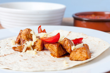 Chicken fajita wrap laying open and topped with grated cheese