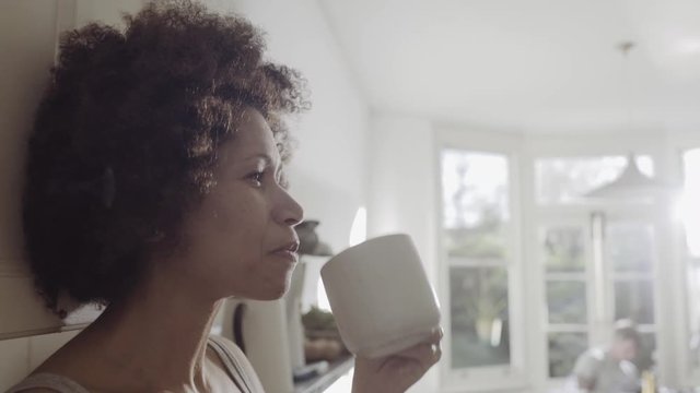 Afro American woman in kitchen enjoying coffee in the morning