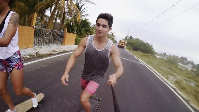 Man holding monopod and enjoying skateboarding with friend on street