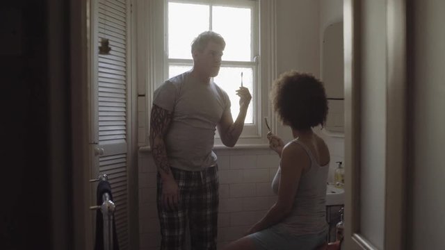 Mixed Race Couple in bathroom arguing and brushing teeth