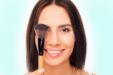 Close up portrait of pretty woman holding makeup brush near eye
