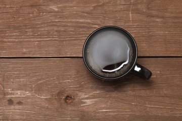 Black cup of coffee on old wooden table