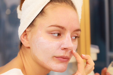 Woman applying mask cream on face in bathroom